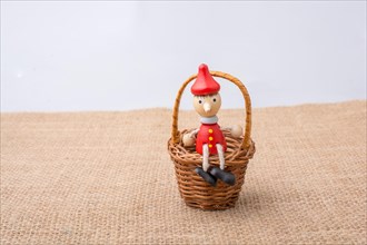 Pinocchio sitting on mini basket on canvas