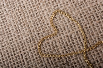 Heart shape formed out of gold color chain on canvas