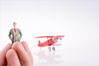 Hand holding red plane with a human figure on a white background