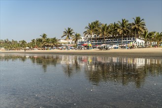 Palm trees on Kotu beach at Paradise Beach Bar and Restaurant reflected in the shallow water at low tide