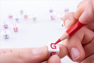 Hand holding pencil with Letter cubes on a white background
