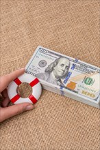 Life preserver in hand over the banknote bundle of US dollar