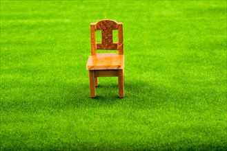 Little model wooden chair on green fake grass