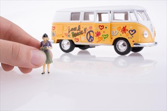 Hand holding a human figure near a peace van on a white background