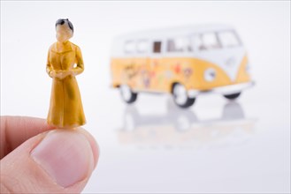 Hand holding a human figure near a peace van on a white background