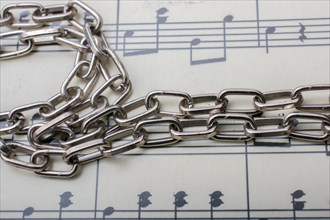 Metal chain placed on a paper with musical notes
