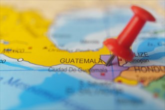 Guatemala marked with a red thumbtack on a map with an out-of-focus background