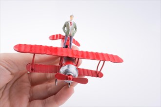 Hand holding red plane with a human figure on a white background