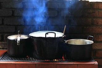 Three cooking pots on a cooker in an open-air kitchen
