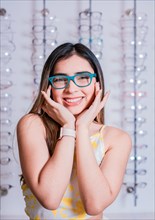 Portrait of a happy female customer wearing glasses in an eyewear store. Smiling girl wearing glasses in an eyeglass store