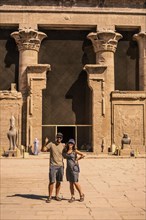 A tourist couple leaving the Edfu Temple near the Nile River in Aswan. Egypt
