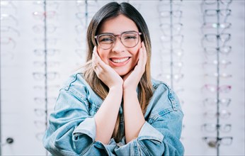 Happy girl modeling glasses in an optical lens store. Portrait of beautiful girl modeling glasses in an optical store