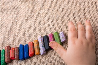 Toddlers hand putting crayons in line on canvas