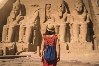 A young tourist in a red dress entering the Abu Simbel Temple in southern Egypt in Nubia next to Lake Nasser. Temple of Pharaoh Ramses II