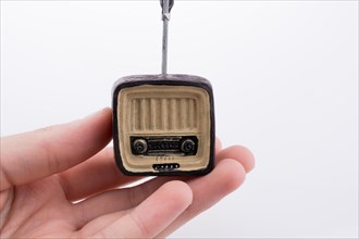 Hand holding a retro TV model on a white background