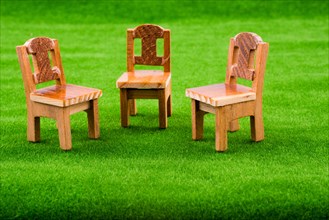 Little model wooden chairs on green fake grass
