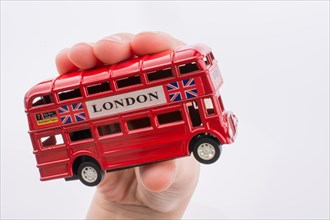 Hand holding a London double decker bus on a white background