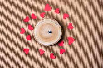 Bead on Piece of log with red paper hearts on cardboard
