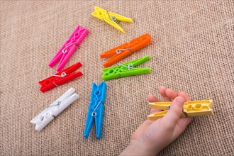 Color clothespin in hand on a linen canvas background