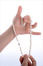 Hand holding a pearl necklace on a white background