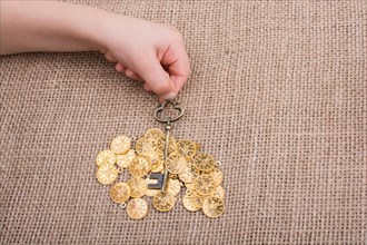 Hand holding a retro styled key over fake gold coins