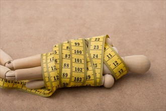 Yellow color measuring tape wrapped on wooden man