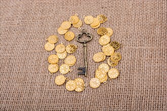 Hand holding a retro styled key over fake gold coins