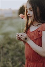 Girl in a red dress in a poppy meadow