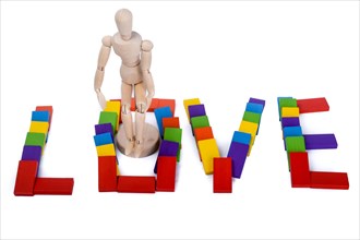 Wooden puppet standing amoung colorful dominos which write love