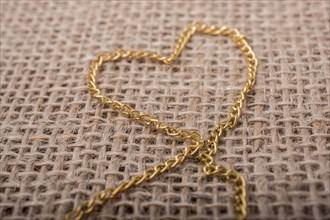Heart shape formed out of gold color chain on canvas