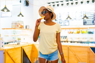 Portrait of African black ethnicity woman eating a mango ice cream in a shop