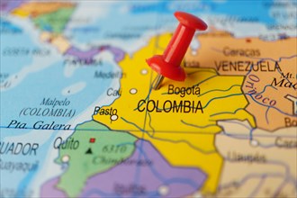 Colombia marked with a red thumbtack on a map with an out-of-focus background