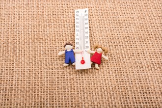 Thermometer placed between a boy and a girl figurine