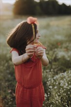 Girl in a red dress in a poppy meadow