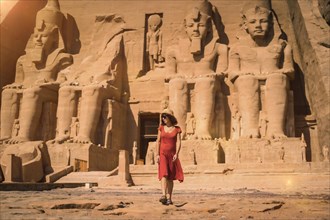 A young tourist in a red dress leaving the Abu Simbel Temple in southern Egypt in Nubia next to Lake Nasser. Temple of Pharaoh Ramses II