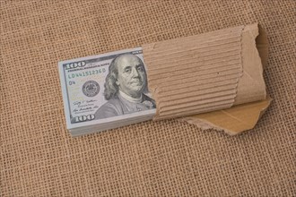 Banknote bundle of US dollar partly wrapped in cardboard