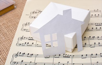 Paper house placed on a paper with musical notes