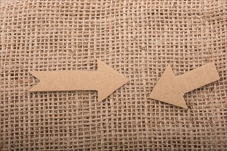 Arrow sign cut out of brown paper on canvas