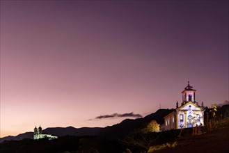 Image with baroque style illuminated churches on top of the hill in Ouro Preto