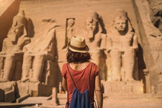 A young tourist in a red dress entering the Abu Simbel Temple in southern Egypt in Nubia next to Lake Nasser. Temple of Pharaoh Ramses II