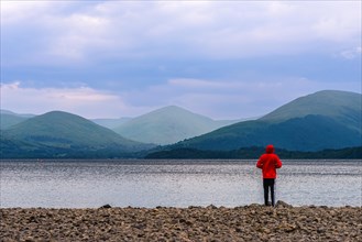 View of Mointains na Boy in a red jacket at Loch Lamond