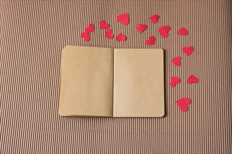 Paper hearts around notebook on cardboard