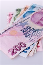 Turkish Lira banknotes by the side of a red color heart shaped object on white background