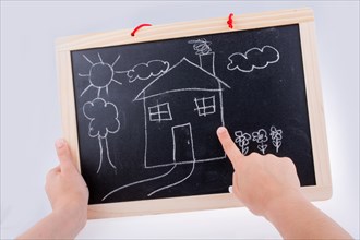 Hand drawing a house on the blackboard with a chalk