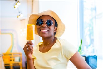Portrait of black African ethnicity woman eating a mango ice cream in a store