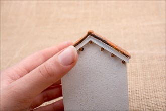 Model house and a hand on a light brown color background