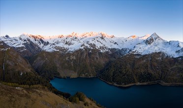 Aerial view over Lago di Luzzone with the first sunlight on the mountain peaks