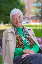 Portrait of an elderly woman sitting on a chair in the garden of a nursing home
