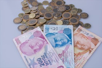 Turkish Lira coins and banknotes side by side on white background