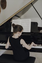 Elegant girl sits at the concert grand and plays the piano